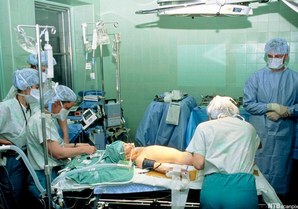 Operasjonssal med leger og sykepleiere ved en ung pasient. Foto.