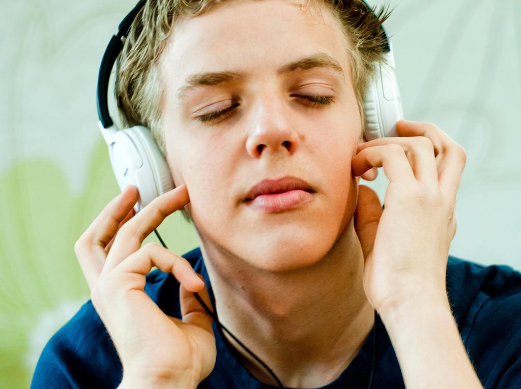 Foto av gutt med øreklokker som lytter med lukkede øyne.