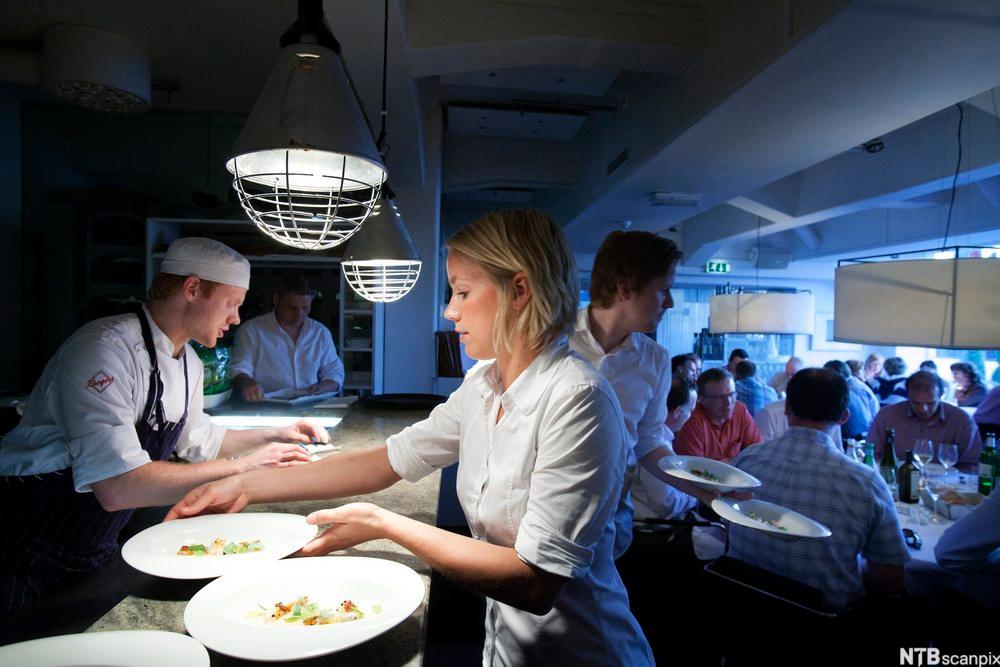 Kokker og servitører samarbeider under middagsservering på en restaurant. Foto.