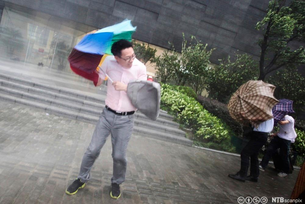 Mann med paraply i sterk vind. Foto.