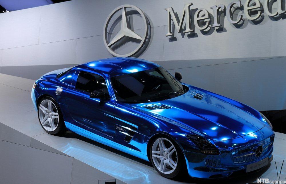 En strøken blå Mercedes på en bilmesse. Firmanavnet er på veggen i bakgrunnen. Foto.