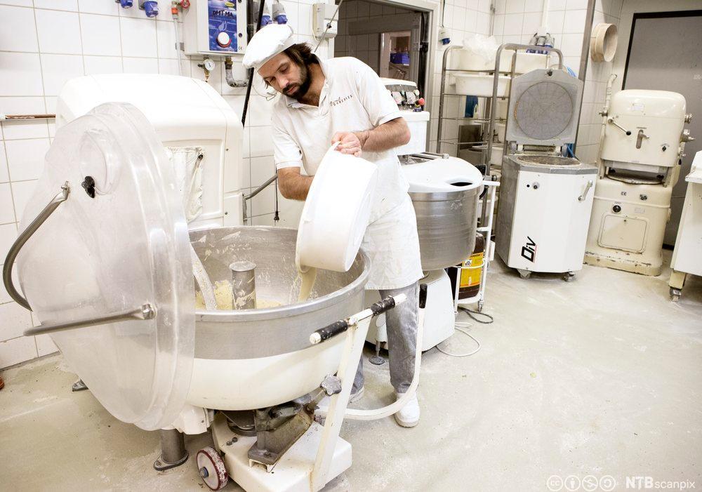 Baker lager gjærbakst i en stor miksmaster. Foto.