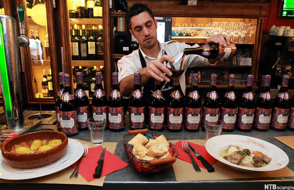 Ein mann heller Beaujolais Nouveau i eit glas i ein bar i Bayonne. Foto.