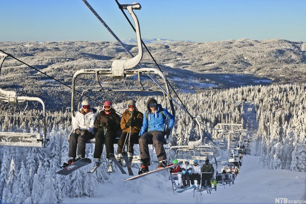Oversiktsbilde av mennesker som sitter i stolheis med alpinski på beina. Foto.