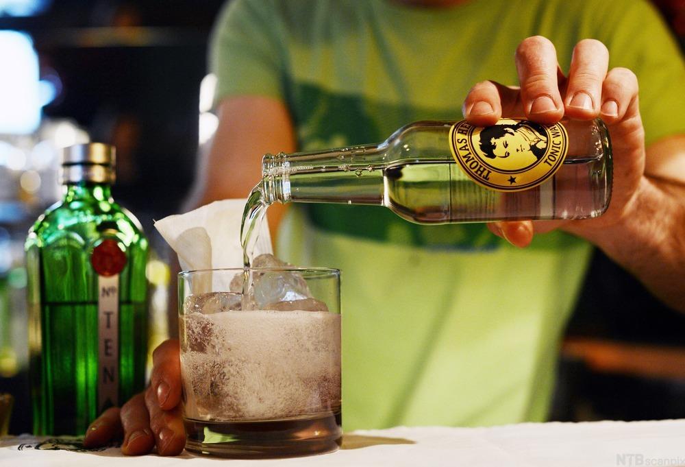 Ein bartender heller tonicvatn i ein drink. Foto.
