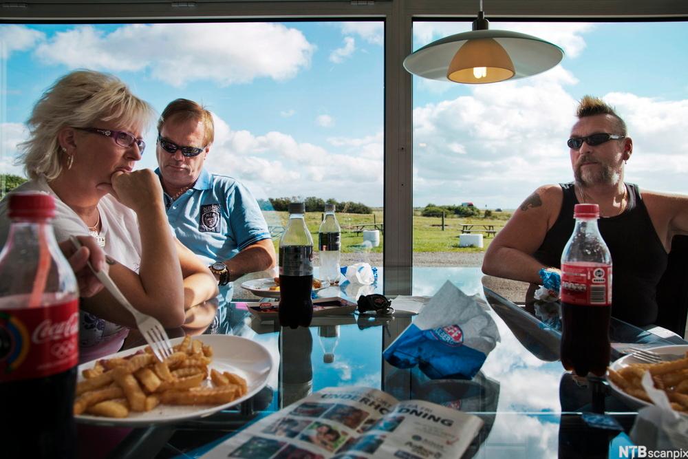 Tre voksne sitter på en cafe. Foto.