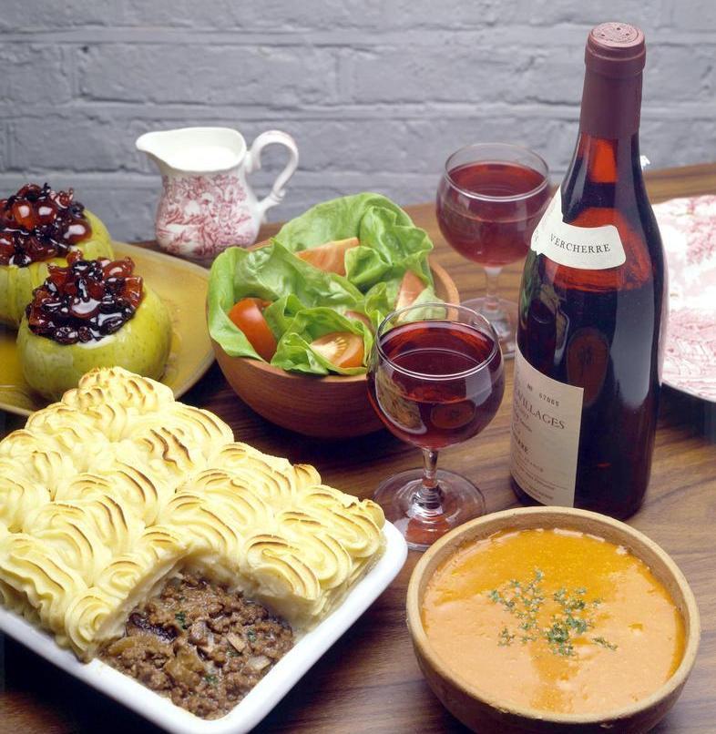 Et bord med ei form med shepherd's pai, salat og ei flaske rødvin. Foto.