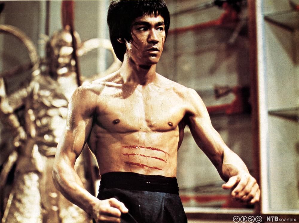 Skuespiller Bruce Lee i bar overkropp med tre blodstiper over magen fra filmen Enter the Dragon. Foto.