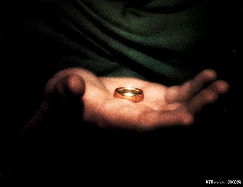 Photo: Light falling on a and holding gold ring, everything else in the picture is dark. 