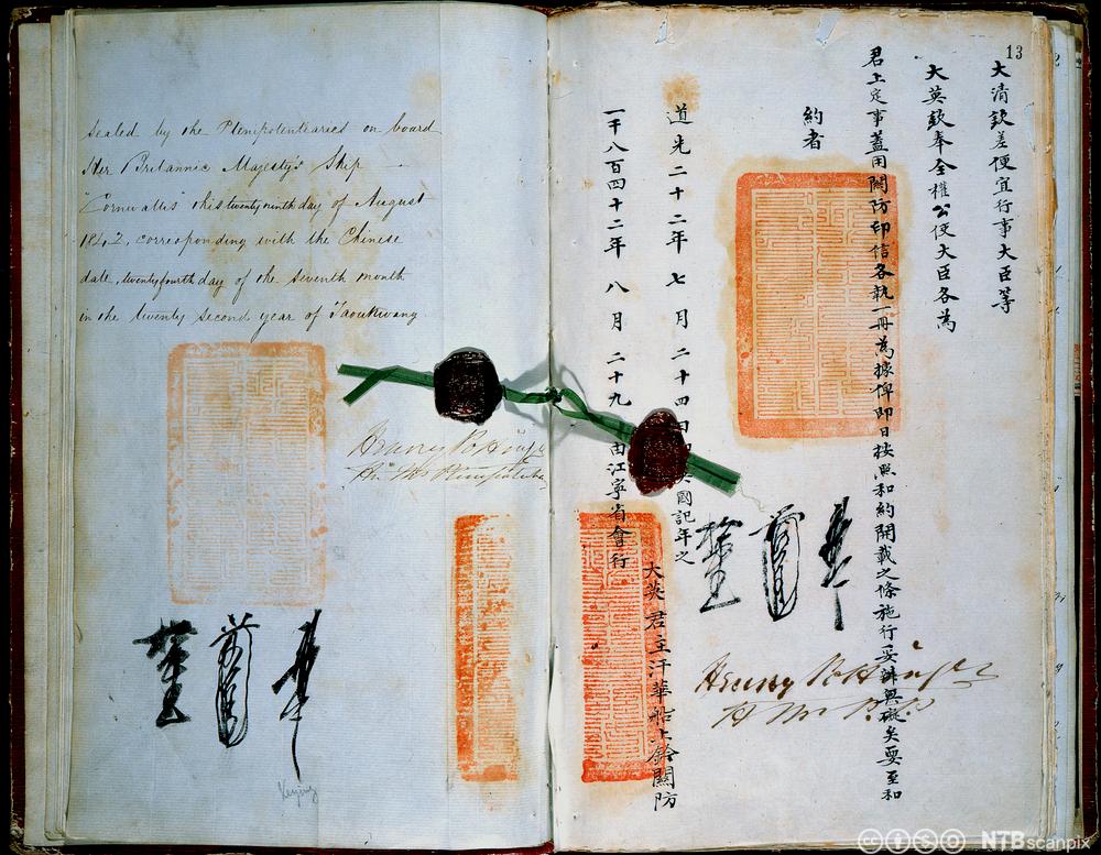 Et eldre dokument med håndskrevne sider: latinske bokstaver på venstre side og kinesiske kalligrafi-tegn på høyre side. Det er underskrifter og stempler på begge sider. Fotografi.