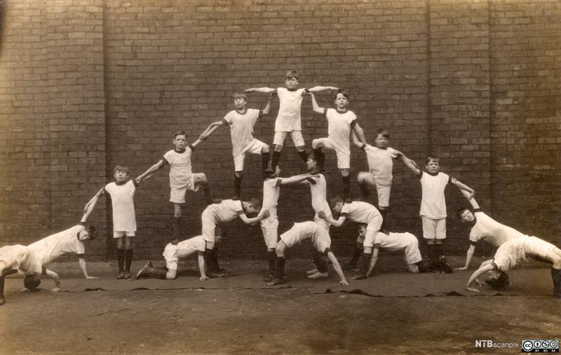 Historisk bilde av gutter som lager en menneskelig pyramide. Foto.