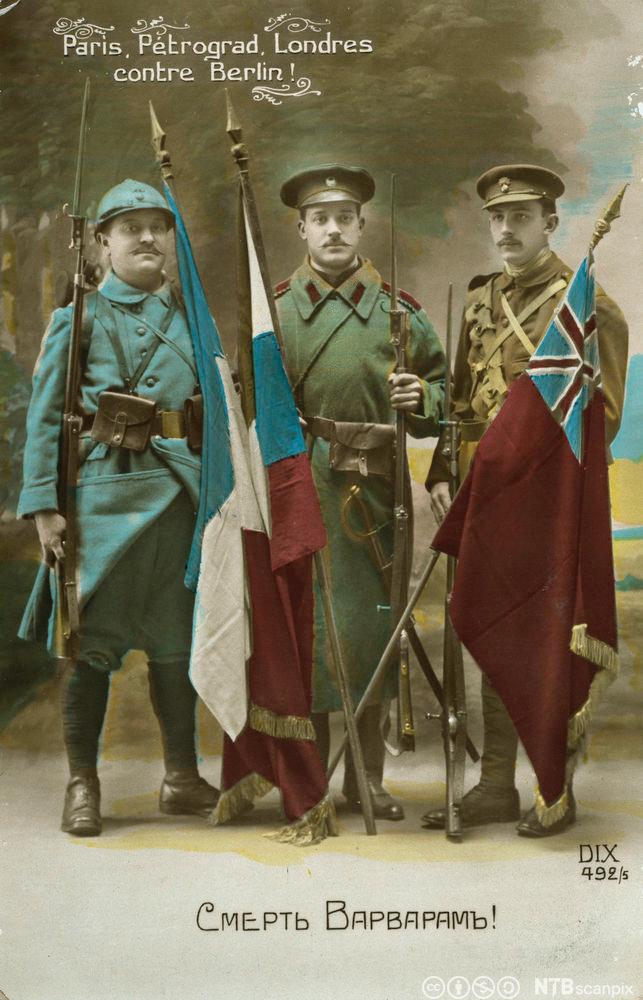 Tre soldater med hvert sitt flagg som symbol på trippelententen: Frankrike, Russland og Storbritannia. Foto av postkort.