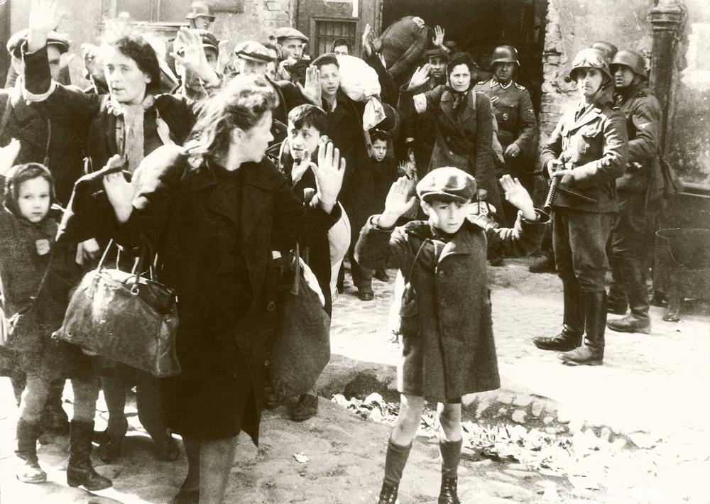Jødiske kvinner og barn føres bort fra gettoen overvåket av bevepnede SS-soldater. Foto.