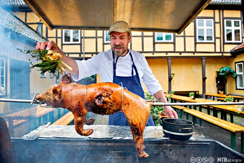 Ein kokk grillar ein heil spegris. Foto.