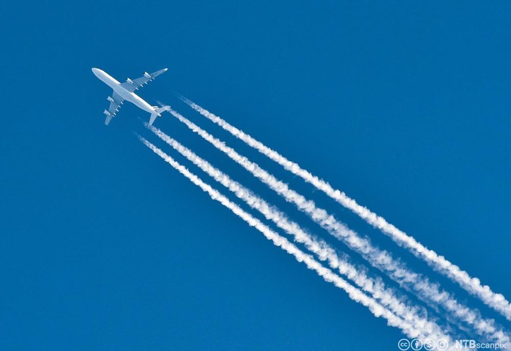 Et fly med kondensstriper etter seg på en klar og blå himmel. Foto. 