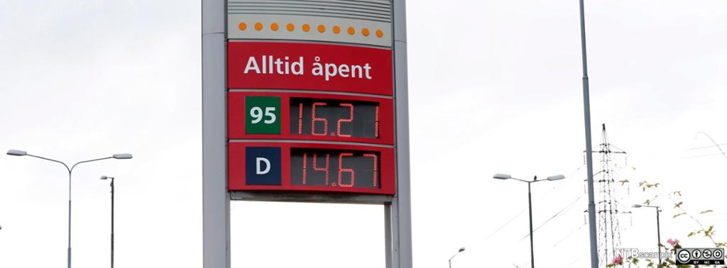 Ei lystavle viser de gjeldende prisene på bensin og diesel ved en bensinstasjon. Øverst på skiltet står det "Alltid åpent". Foto. 