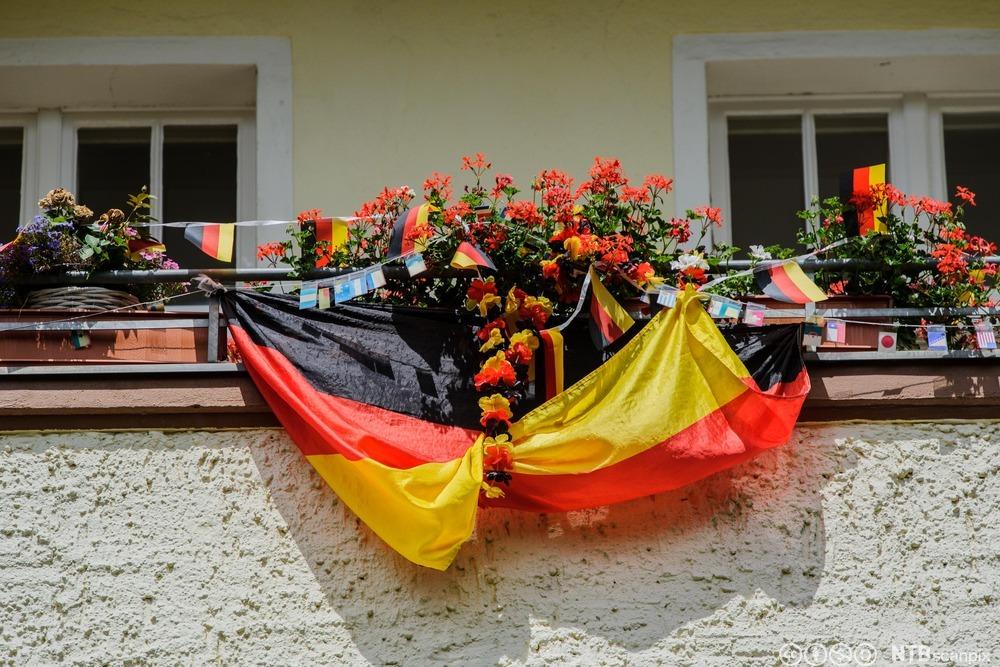 Tysk flagg som er drapert utafor en balkong i ei boligblokk. Foto.