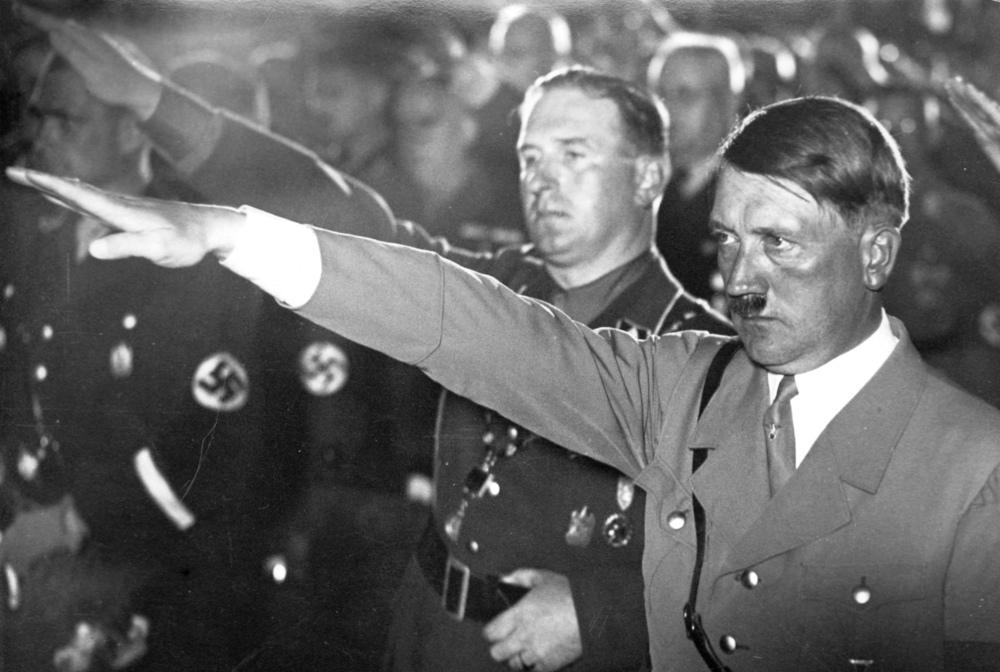 Adolf Hitler og andre menn i naziuniform gjer nazi-helsing. Foto.
