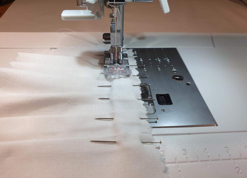 Fotografi av at en prøvelapp med folder blir sydd på maskin.