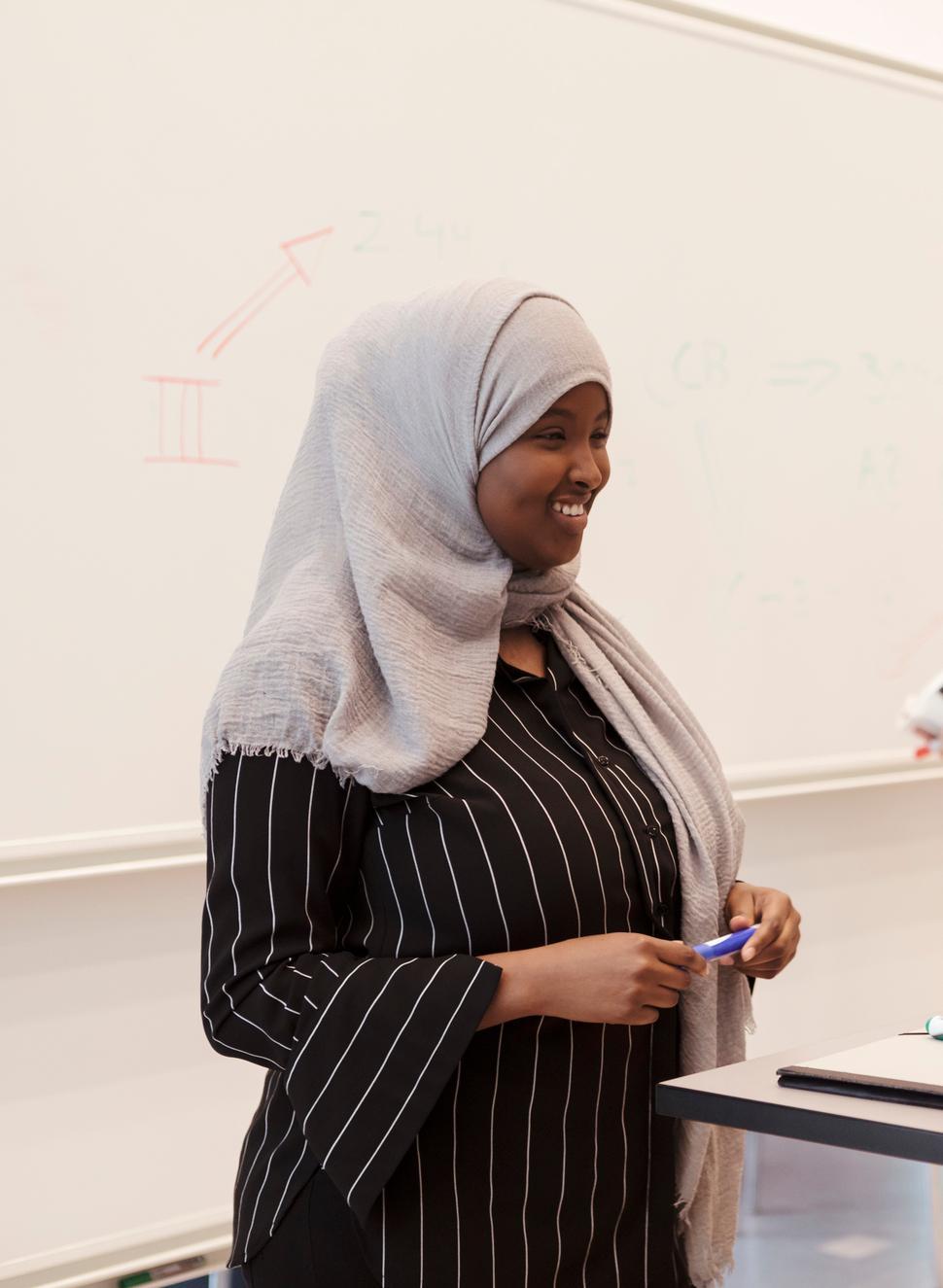 Ung, mørkhudet kvinne med hidsjab holder presentasjon. Foto.