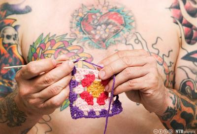 Mann med tatovering hekler. Foto.