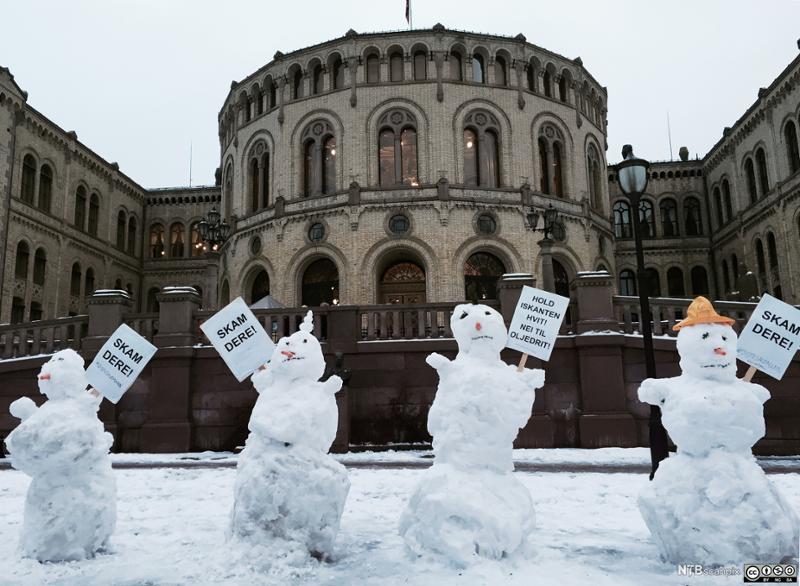 Snømenn protesterer med plakater foran Stortinget. Foto.