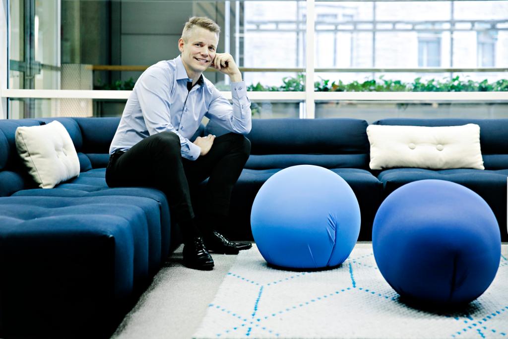 Sondre Gravir, per 2021 leder i finn.no, sitter i en sofa i et kontorlandskap. Foto.