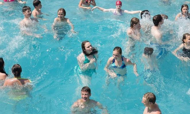Foto av mange unge menneske som badar i eit utandørs badeanlegg i Tyskland.