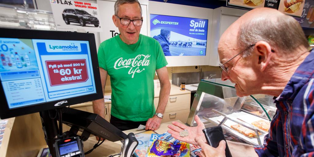Mann betaler med mynter i en kiosk. Foto.