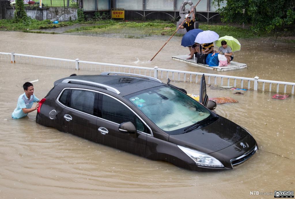 Bil blir dyttet i oversvømt gate etter en tyfon i Fuzhou, Fujian, Kina, 2015. Foto.