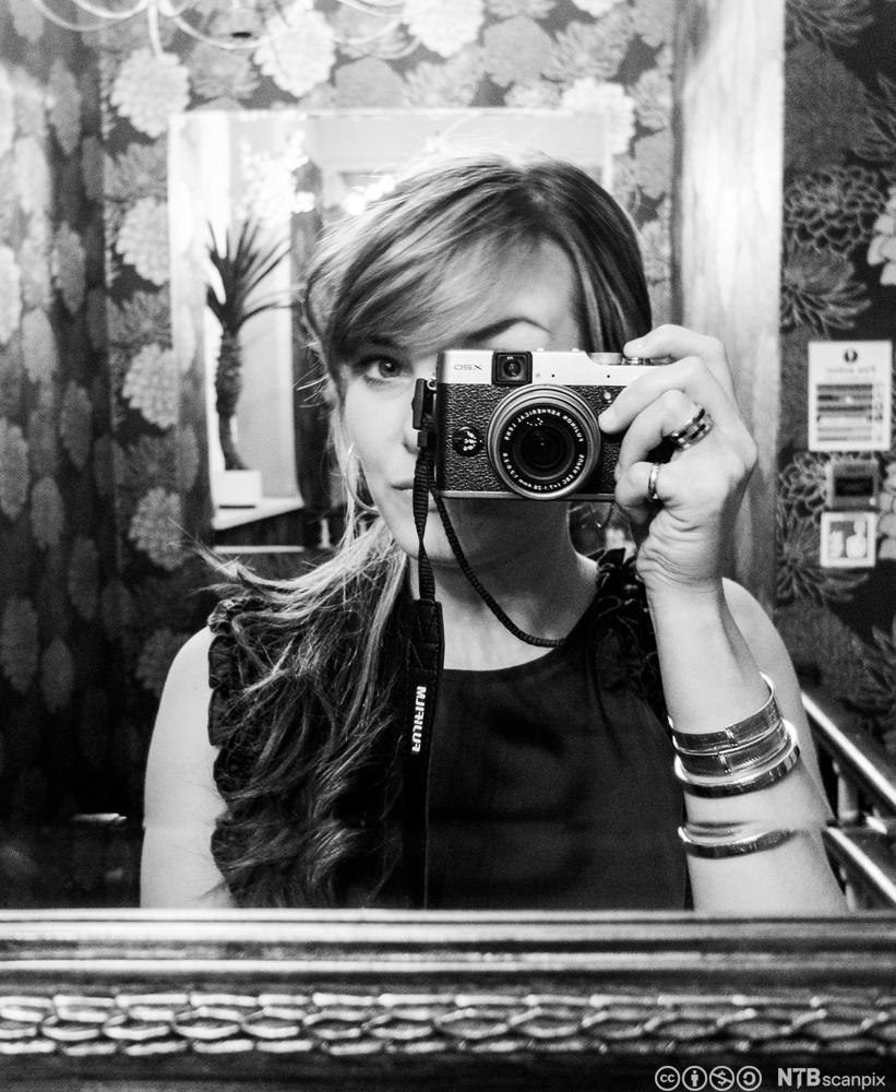Kvinne som fotofraferer seg selv i et speil. Foto.