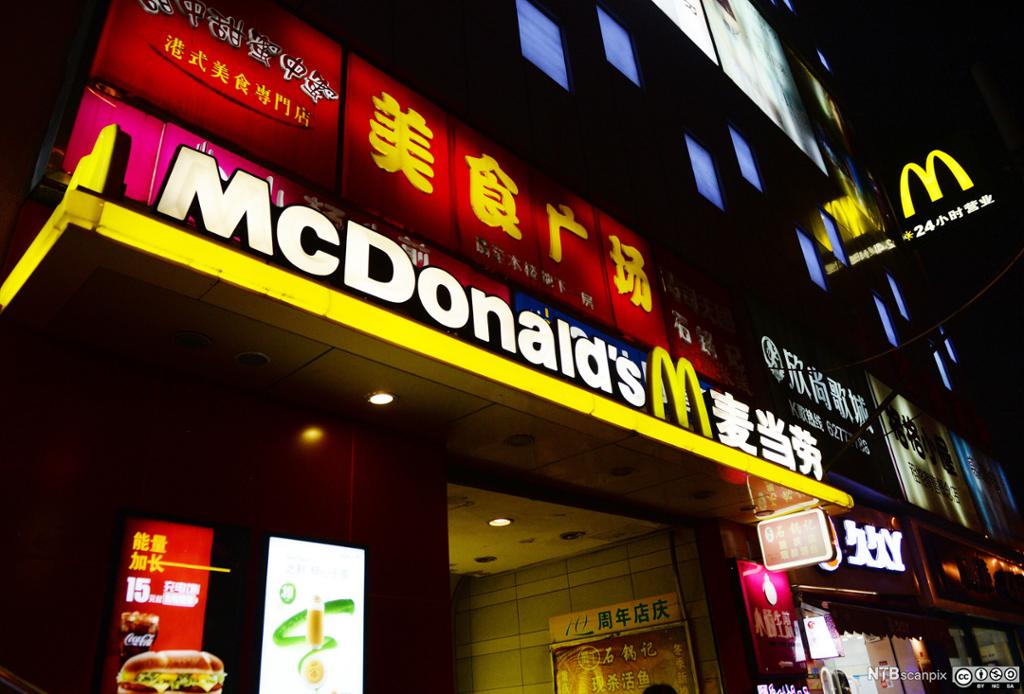 Inngang til McDonald's-restaurant i Shanghai. Logoen er laga i sterke fargar og med neonlys. Sjølve namnet McDonald er skrive med bokstavar, mens det òg er kinesisk skrift på delar av inngangspartiet. Foto.