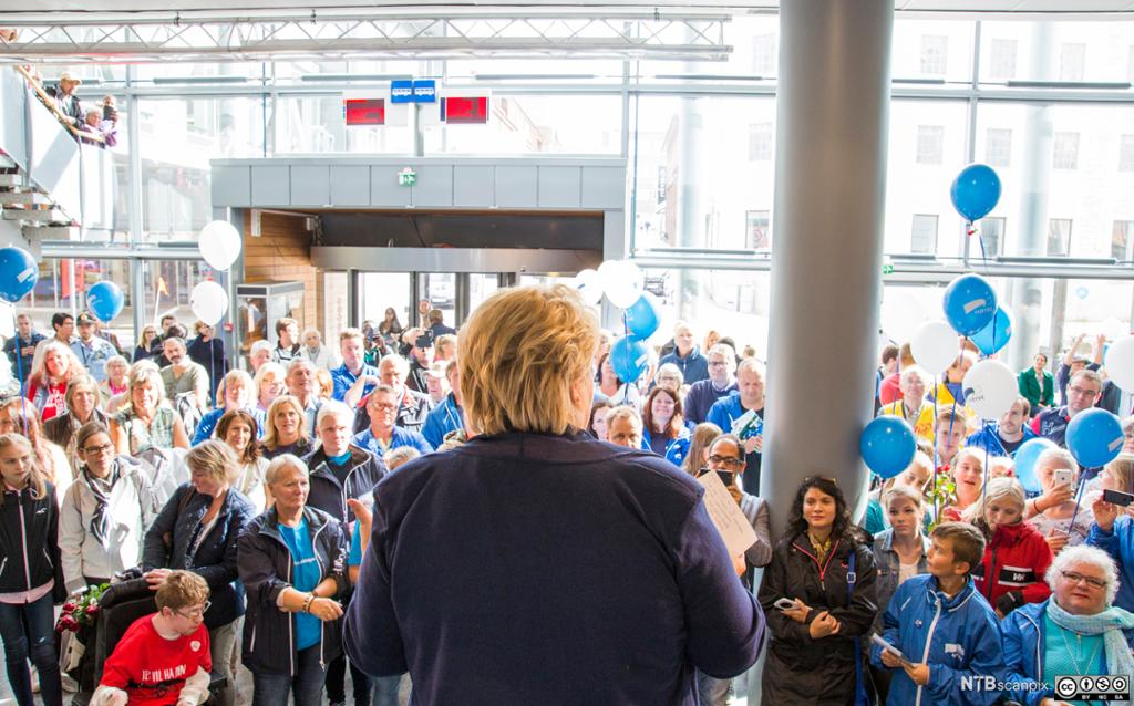 Erna Solberg står med ryggen til framfor ein tilhøyrarskare. Foto.