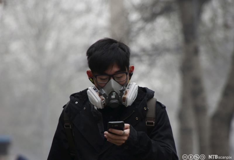 Mann har på seg kraftig maske som følge av forurensing i Beijing. Foto.