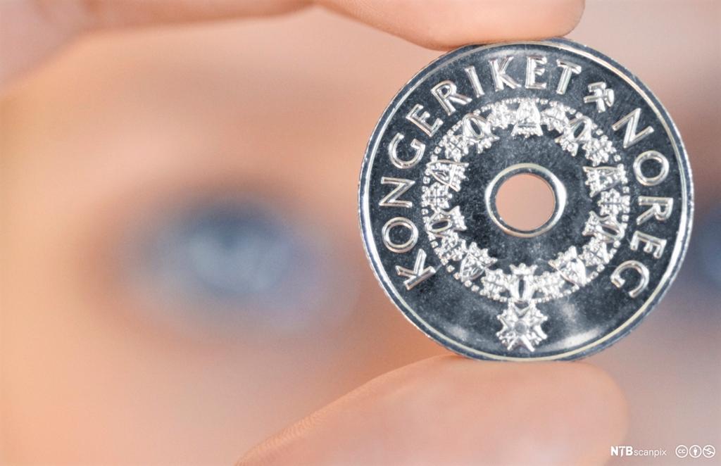 Kronestykke med uklart ansikt i bakgrunnen. Foto.