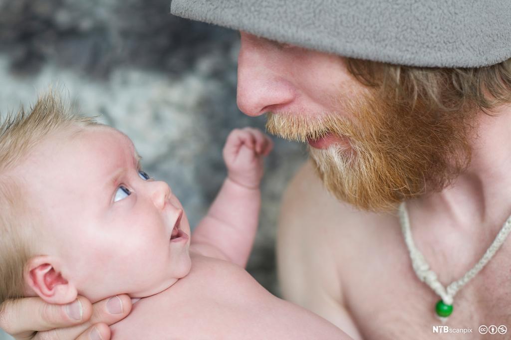 En ung man prater med en baby. Foto