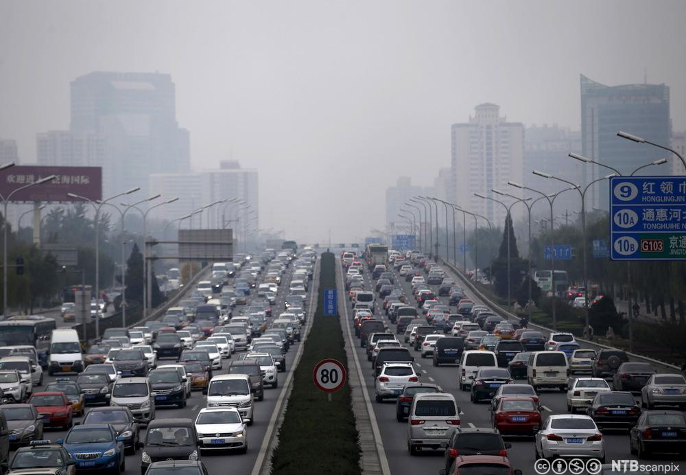 Tett trafikk av bilar med eit lok av forureina luft over Beijing. Foto.