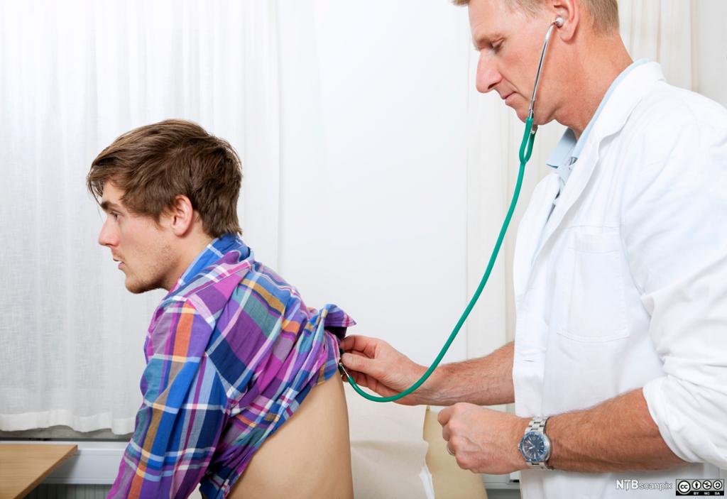 Lege lytter på ryggen til en mann med stetoskop. Foto.