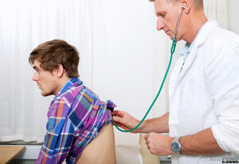 Lege lytter med stetoskop på ryggen til en pasient. Foto.