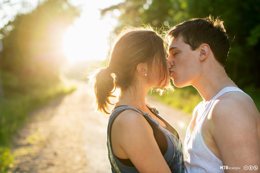 Ei ung dame og en ung mann kysser hverandre. Foto.