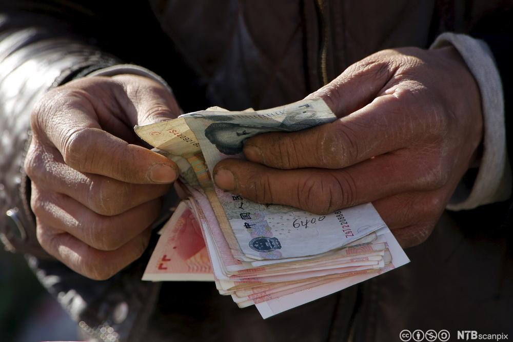 En grønnsaksselger i Bejing teller pengene sine. Foto.