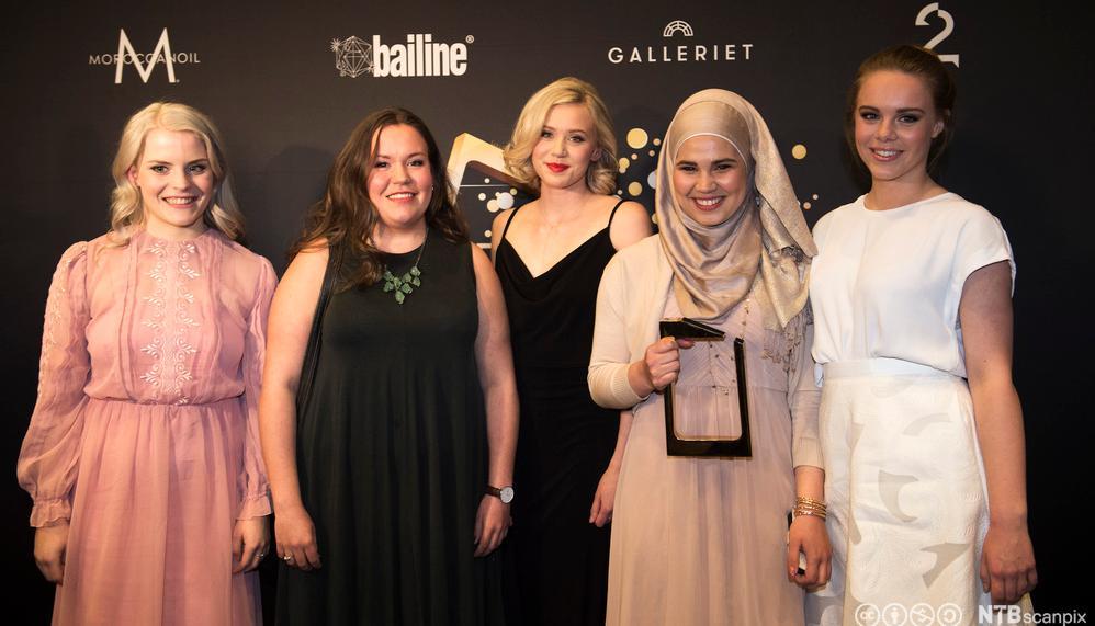 Foto av fem unge, kvinnelege skodespelarar som smiler og held statuetten dei har vunne under ei prisutdeling.