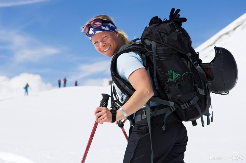 Kvinne med sekk på ryggen går på ski i fjellet. Foto.