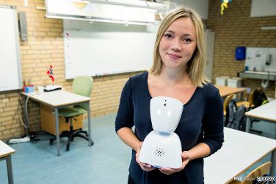 Bilde av teknologigründer Karen Dolva fra selskapet No Isolation som står i et klasserom med  roboten AV1 i hendene. Foto. 