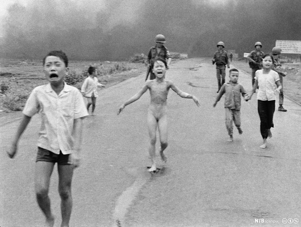 Barn på flukt etter napalmangrep under Vietnamkrigen, 1972. Én av jentene er naken. Soldater kan sees i bakgrunnen. Foto.