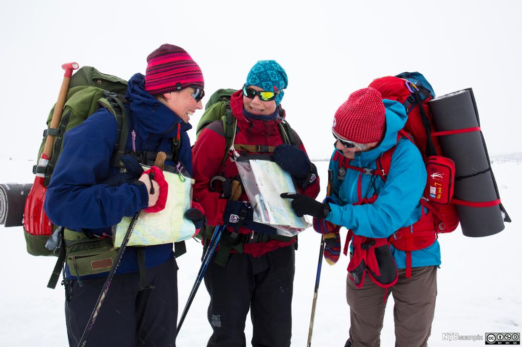 Tre kvinner på skitur i fjellet sjekker kartet. Foto.