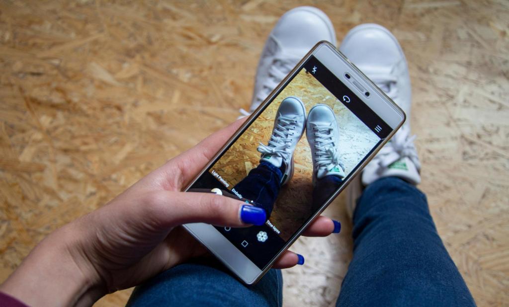 En ung jente tar bilde av joggeskoene sine med mobiltelefon. Foto.