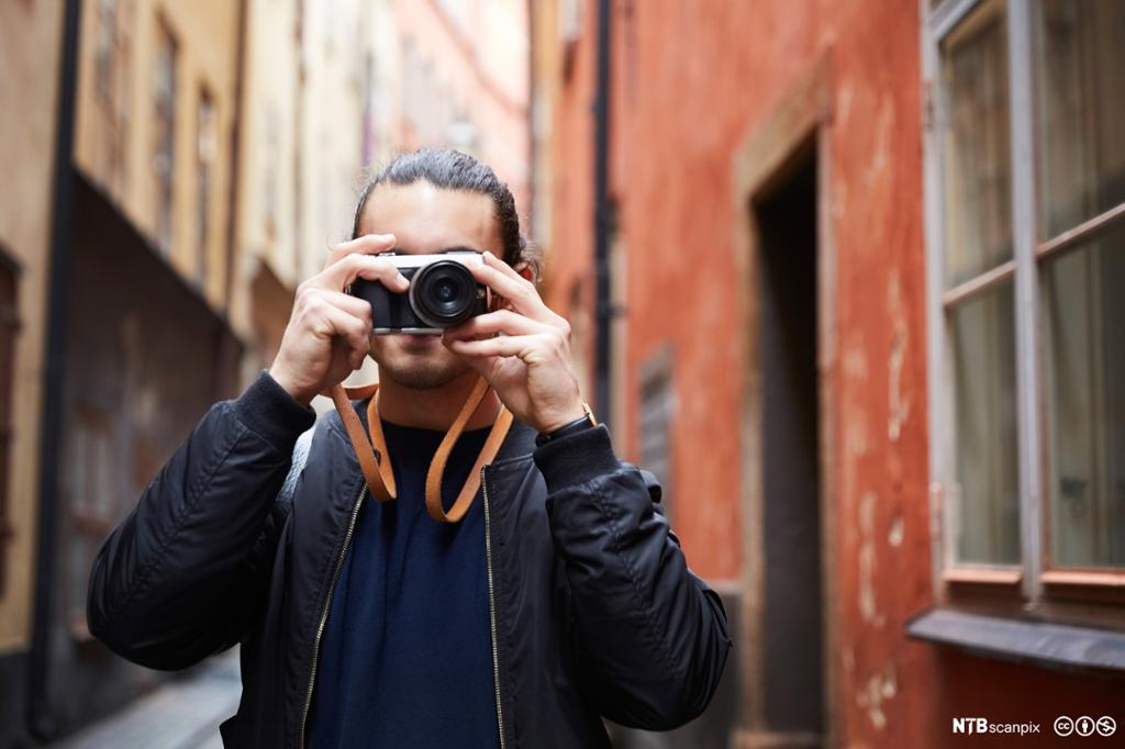 Mann som fotograferer i pittoresk gate. Foto.