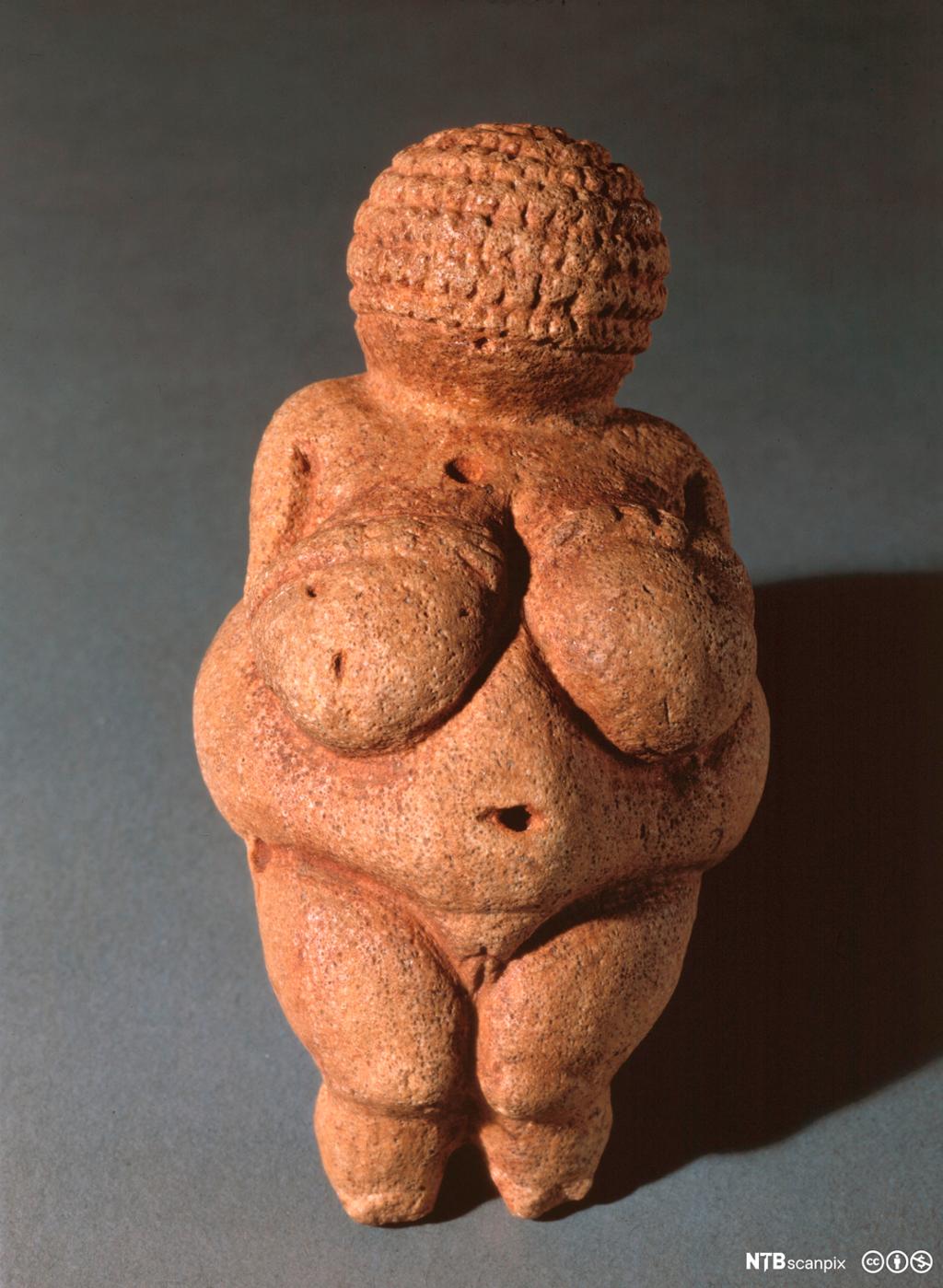 Skulptur av frodig kvinneskikkelse i sandstein. Foto.