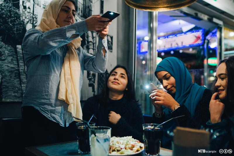 Unge muslimske jenter med hijab på kafe. Foto.